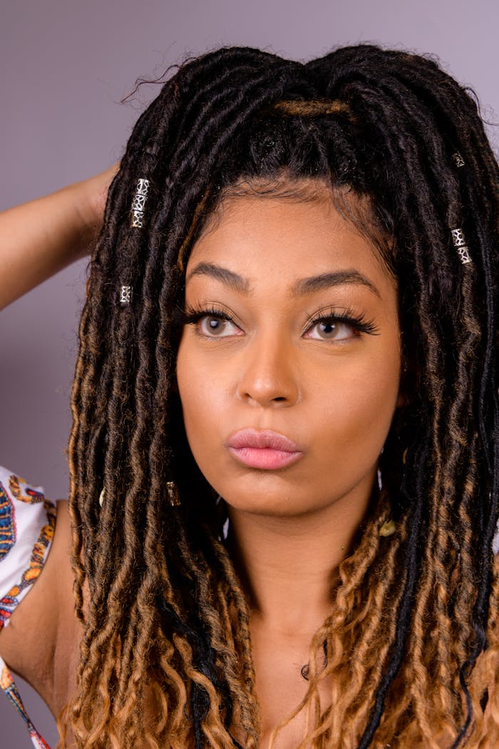 Close-up portrait of a black woman with long dreadlocks looking thoughtful. Vertical shot.