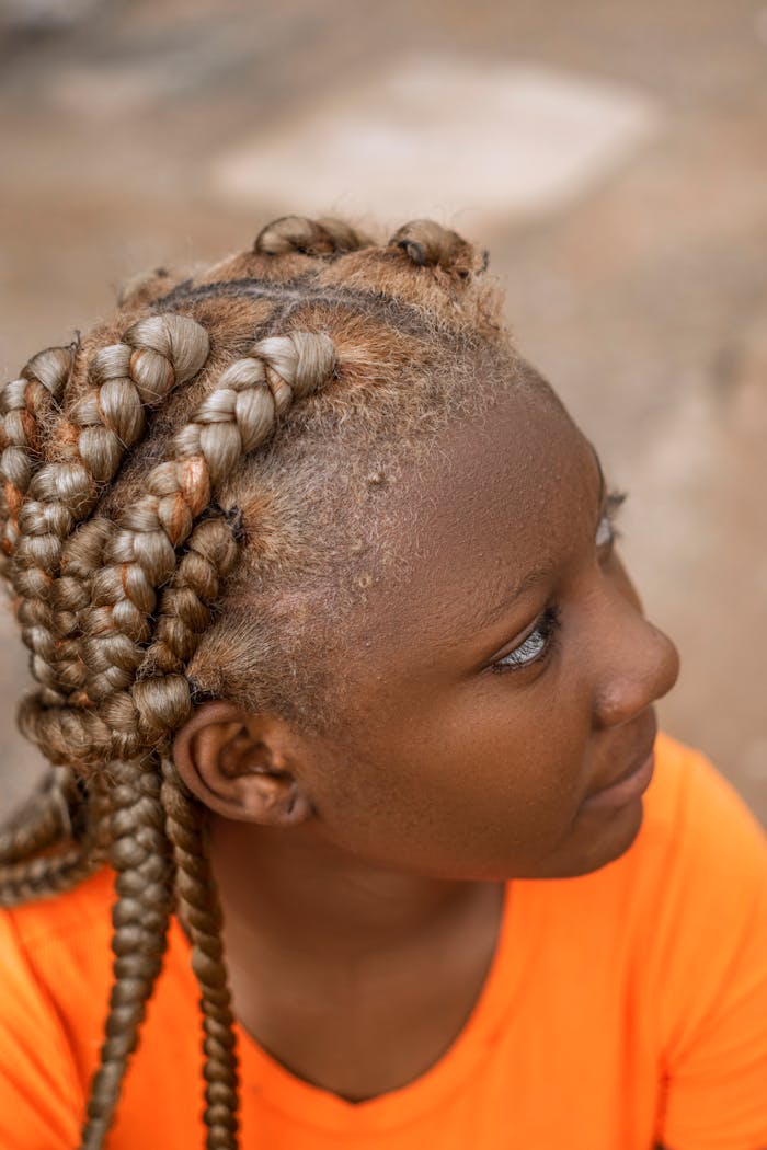 Detailed portrait of an African woman showcasing an intricate braided hairstyle in a natural setting.