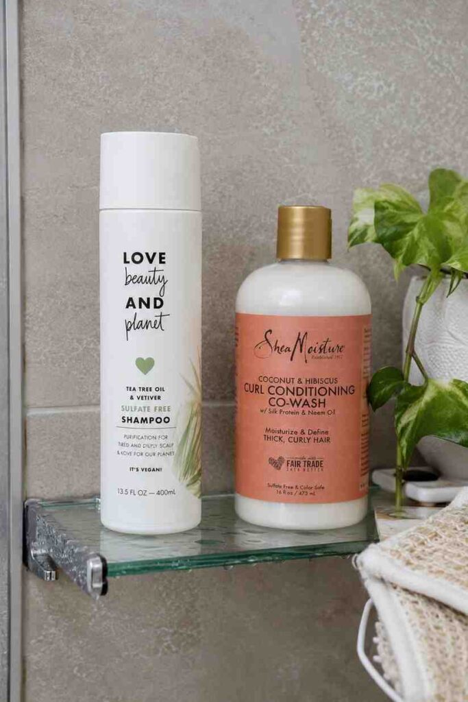 How to do a wash-and-go on 3C hair (beginner guide) Shampoo bottle beside curl-friendly co-wash products on a bathroom shelf.