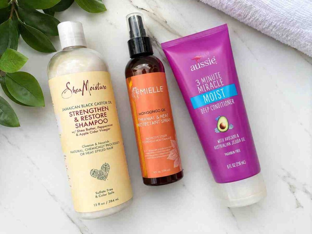 flat lay of sulfate-free shampoo, heat protectant spray, and protein conditioner - products recommended for high porosity hair care routine