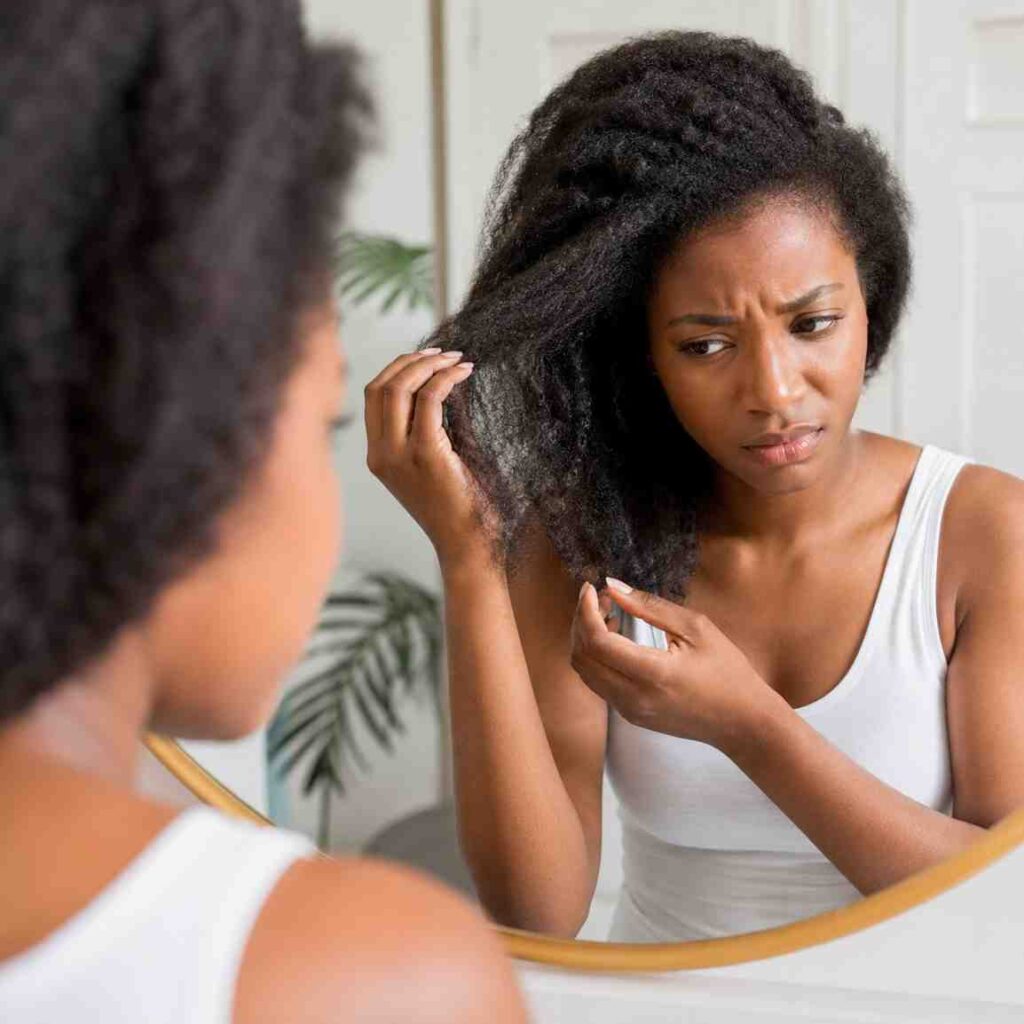 frustrated woman examining dry, frizzy high porosity natural hair in mirror